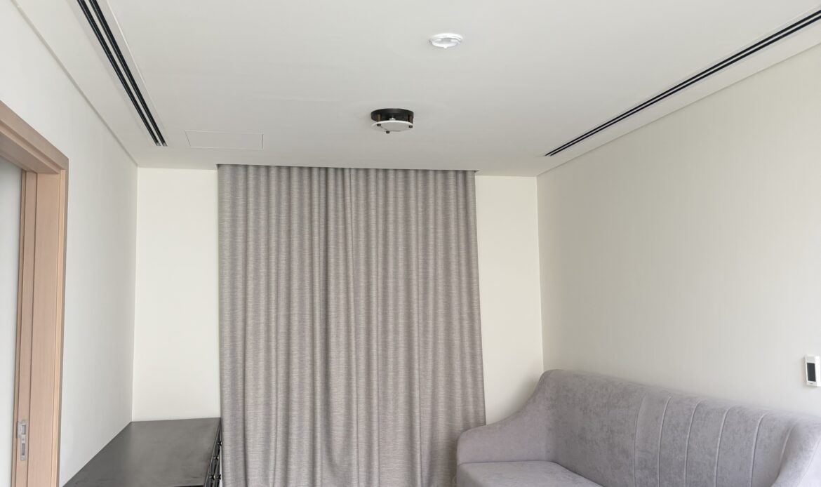 Modern bedroom featuring a bed, armchair, and neutral-colored furnishings