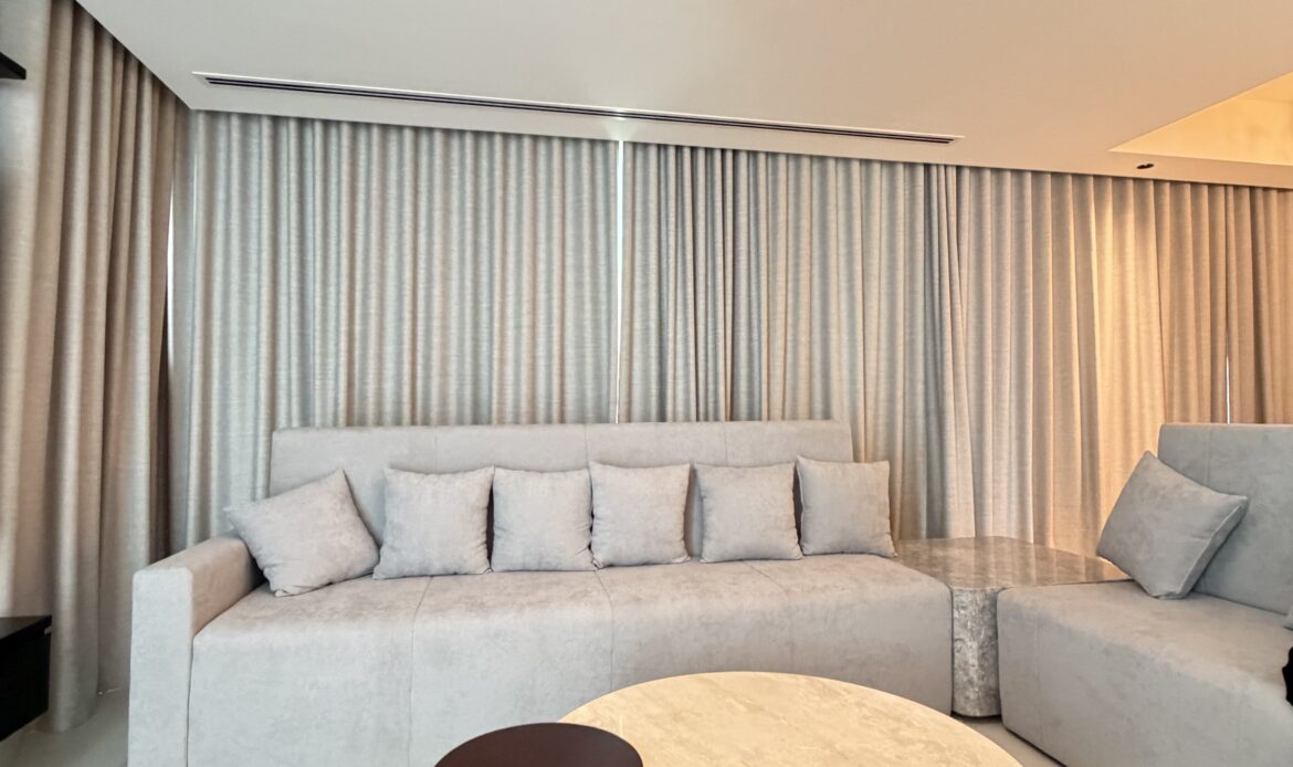 Living room with a curved sofa, round coffee table, and modern ceiling light