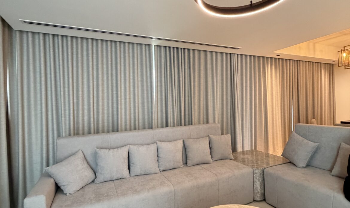 Wide view of a modern living room with sofa, coffee table, and neutral decor